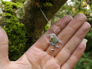 Robin red breast pendant, An Spideog, made of sterling silver. The chain is hanging from a tree branch.