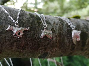 Irish sterling silver horse pendants hanging on a branch. Handmade in Ireland by Elena Brennan.