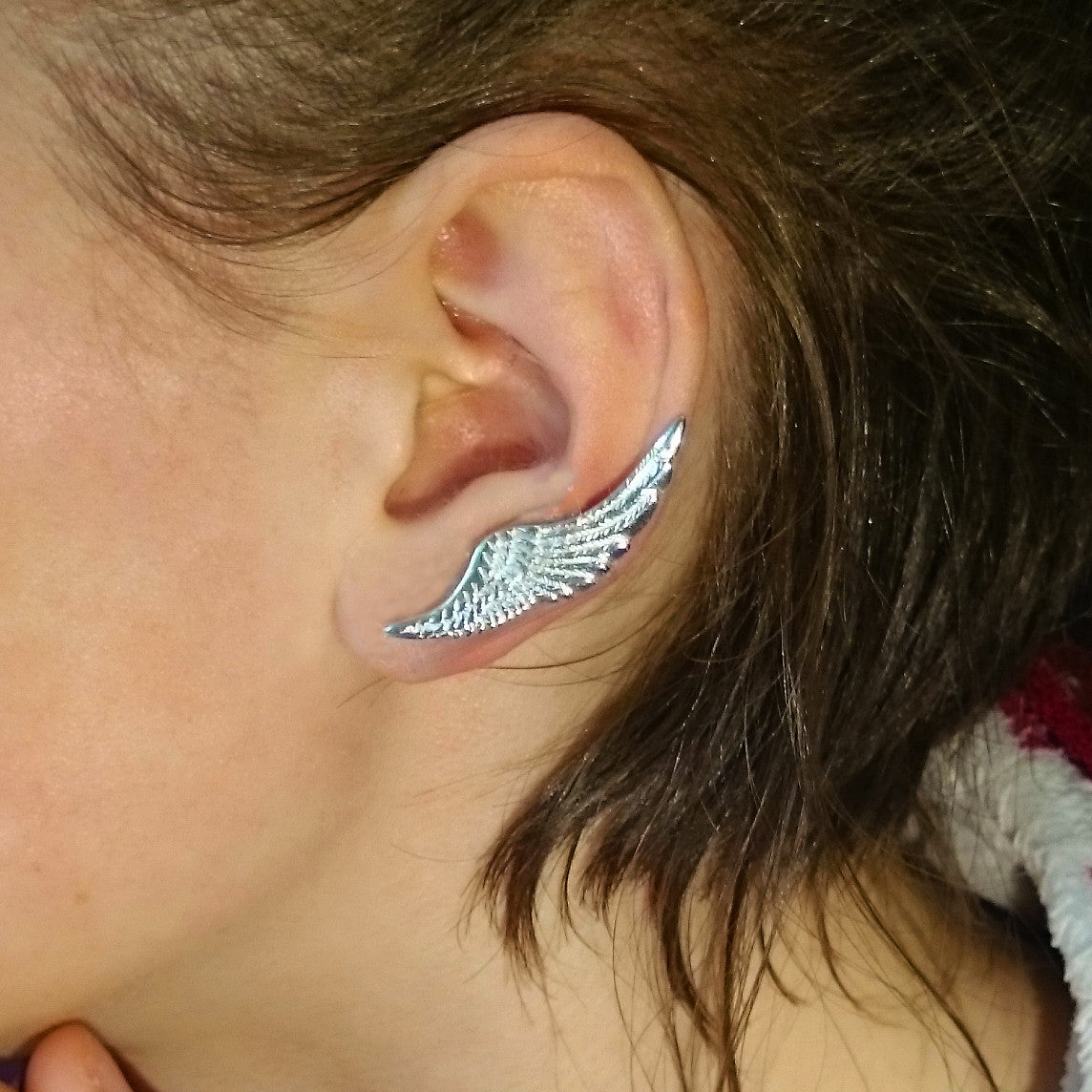 A woman wearing a sterling silver Angel Wings Ear Cuff earring, handmade by Irish jewellery designer Elena Brennan in Cavan, Ireland.