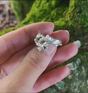 A sterling silver family birthstones ring in the shape of twigs that can also function as an Irish wedding ring or promise ring. The ring is sitting on a mossy tree branch. Handmade in Cavan, Ireland.