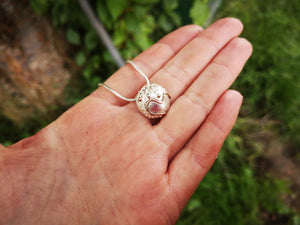 The Small Cúrsa an tSaoil Pendant is dainty as seen on hand for scale.