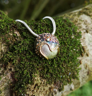 The Small Cúrsa an tSaoil Pendant hand made by Elena Brennan Jewellery on the branch of a tree.