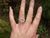 A hand showing off the twiggy family birthstone ring, made of sterling silver. It can also function as an Irish wedding ring or promise ring.